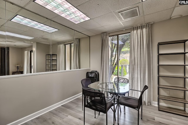 dining area with baseboards, a drop ceiling, and wood finished floors