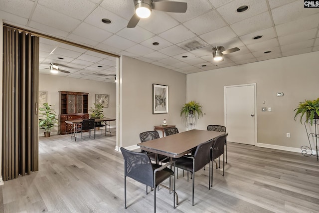 dining room with light wood-type flooring, baseboards, a drop ceiling, and a ceiling fan