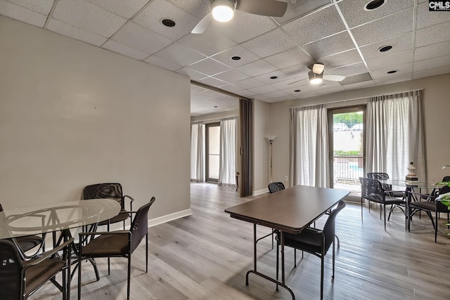 dining area featuring a paneled ceiling, ceiling fan, and light wood finished floors