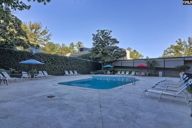 community pool with a patio and fence