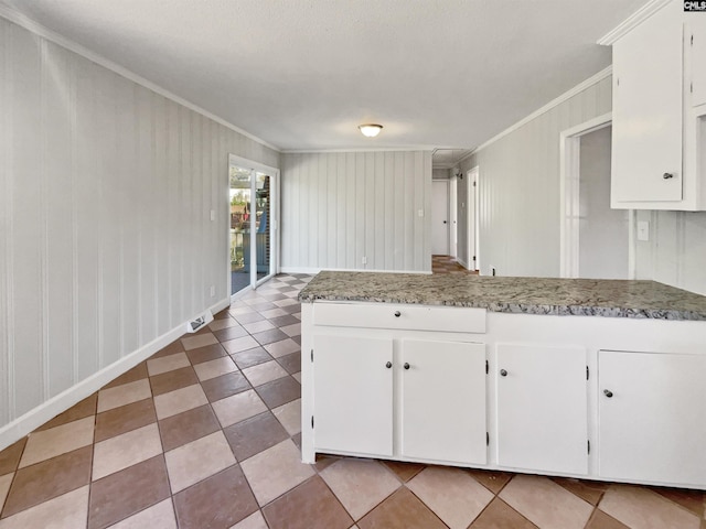 kitchen with white cabinetry, crown molding, a peninsula, and baseboards