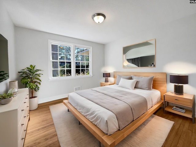 bedroom featuring light wood-type flooring, visible vents, and baseboards