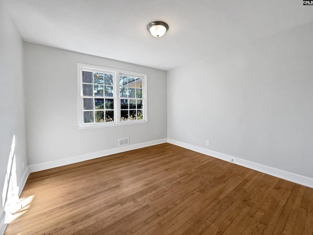 spare room with visible vents, baseboards, and wood finished floors