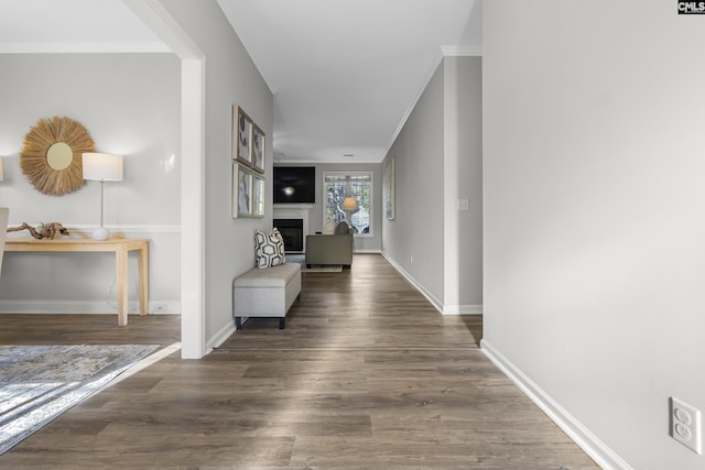 corridor with ornamental molding, wood finished floors, and baseboards