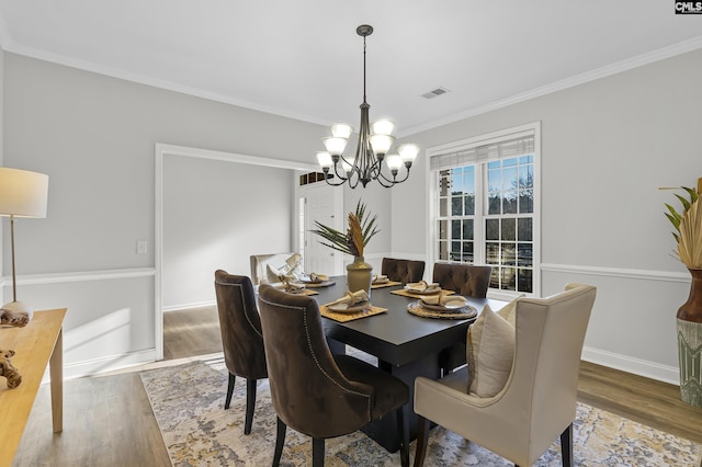 dining room with visible vents, a chandelier, wood finished floors, and ornamental molding