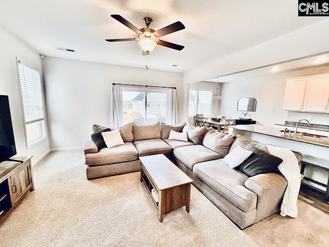 living area featuring a wealth of natural light, light colored carpet, visible vents, and baseboards