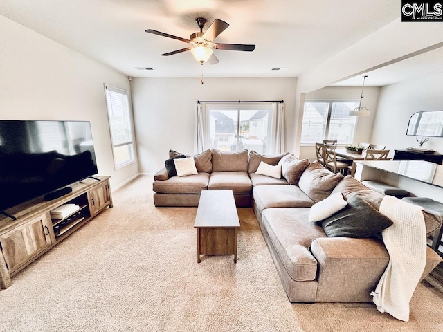 living area featuring a healthy amount of sunlight, light colored carpet, ceiling fan, and visible vents