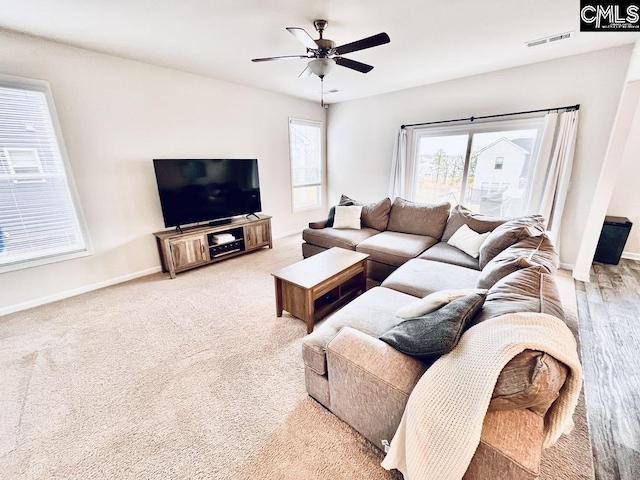 living room with light carpet, baseboards, visible vents, and a ceiling fan