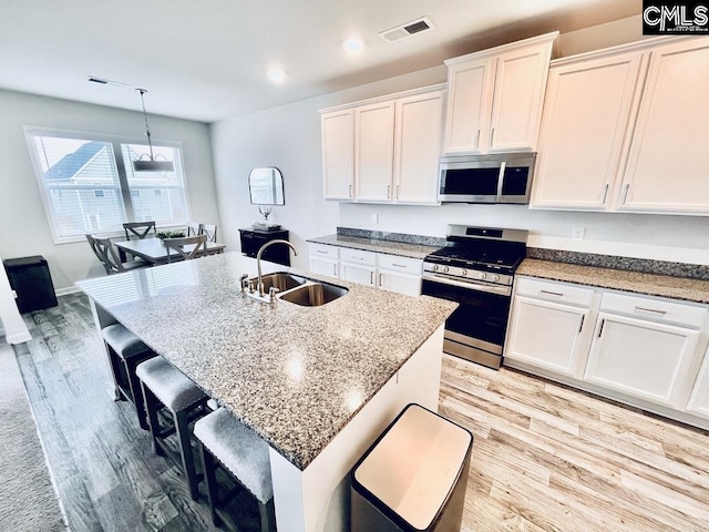 kitchen featuring light wood finished floors, visible vents, white cabinets, appliances with stainless steel finishes, and a sink