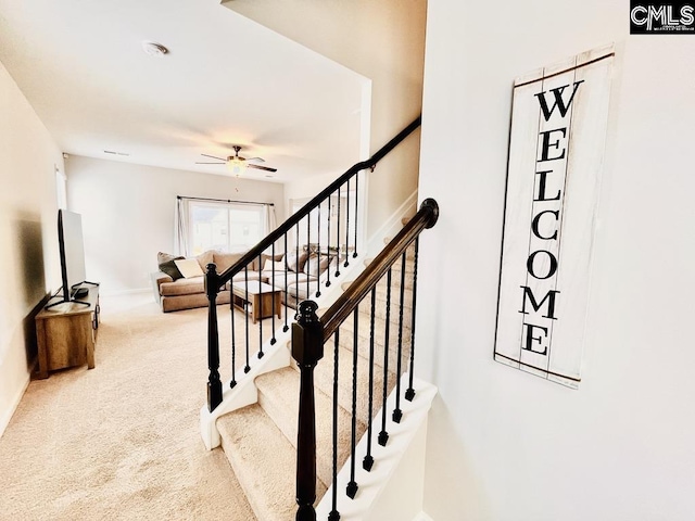 stairway with carpet floors and ceiling fan