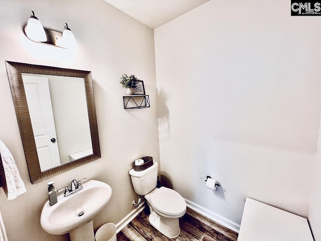 bathroom featuring wood finished floors, a sink, toilet, and baseboards