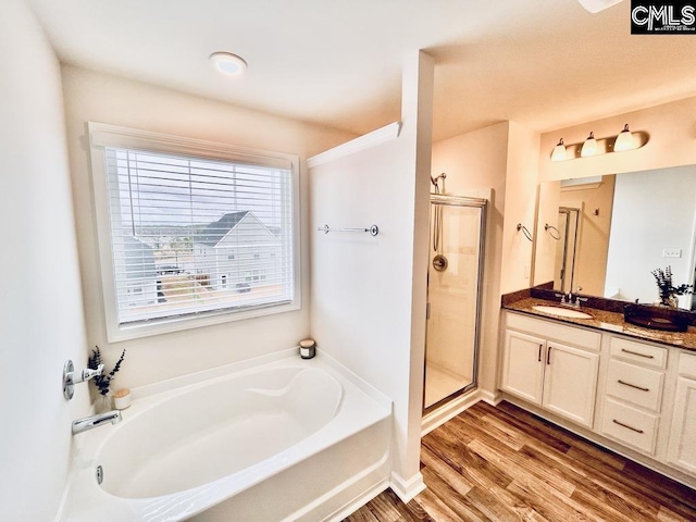 bathroom featuring vanity, wood finished floors, a shower stall, and a bath