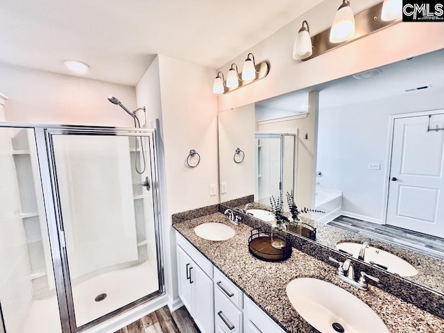 full bathroom featuring a sink, a shower stall, and double vanity