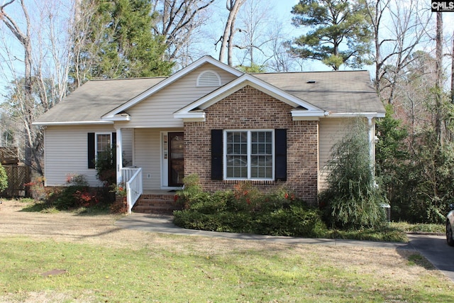 single story home featuring a front yard, covered porch, and brick siding