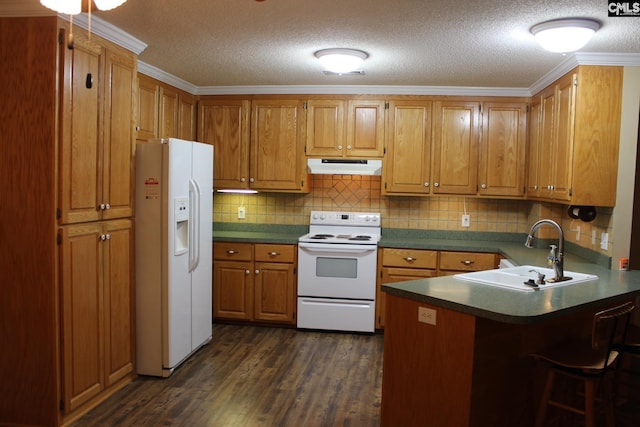 kitchen featuring under cabinet range hood, a peninsula, white appliances, a sink, and brown cabinets