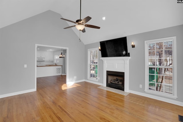 unfurnished living room featuring a fireplace with flush hearth, visible vents, a ceiling fan, baseboards, and light wood-type flooring