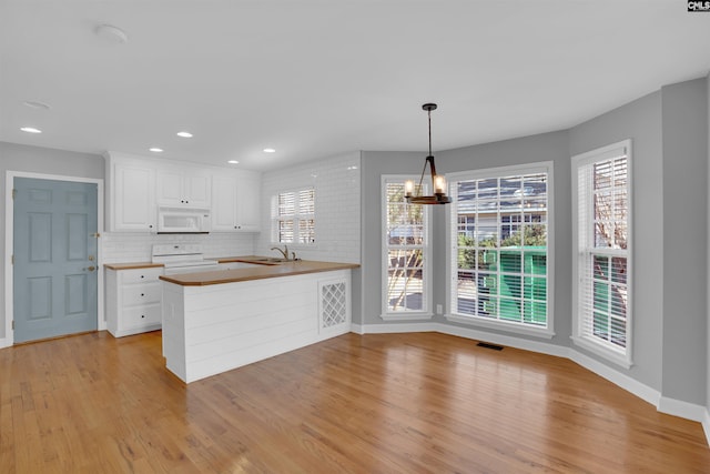 kitchen with electric range, visible vents, white cabinets, white microwave, and a sink