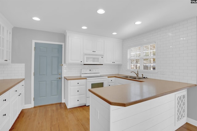 kitchen with a peninsula, white appliances, a sink, visible vents, and light wood-type flooring