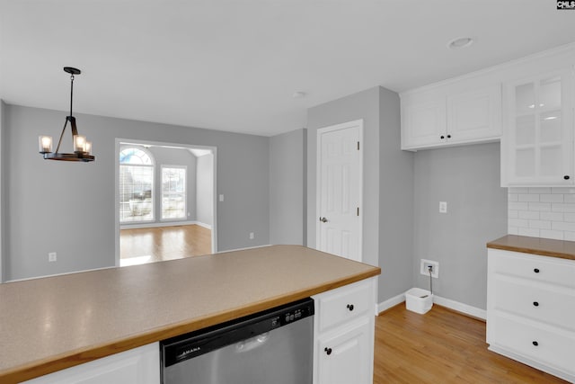 kitchen with white cabinets, hanging light fixtures, stainless steel dishwasher, decorative backsplash, and light wood finished floors