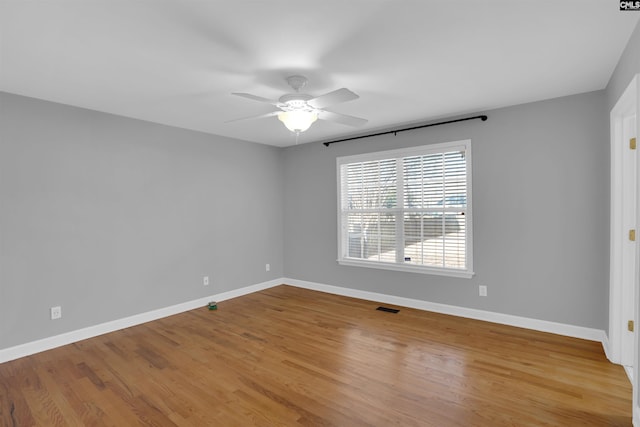 empty room featuring wood finished floors, a ceiling fan, and baseboards