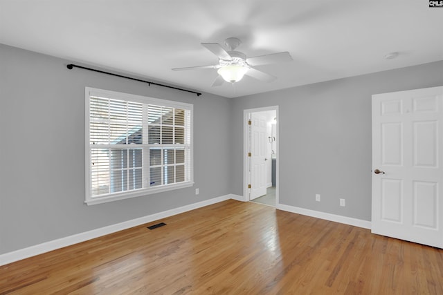 spare room with ceiling fan, light wood finished floors, visible vents, and baseboards