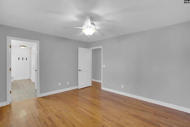 unfurnished bedroom with light wood-type flooring, ceiling fan, baseboards, and connected bathroom