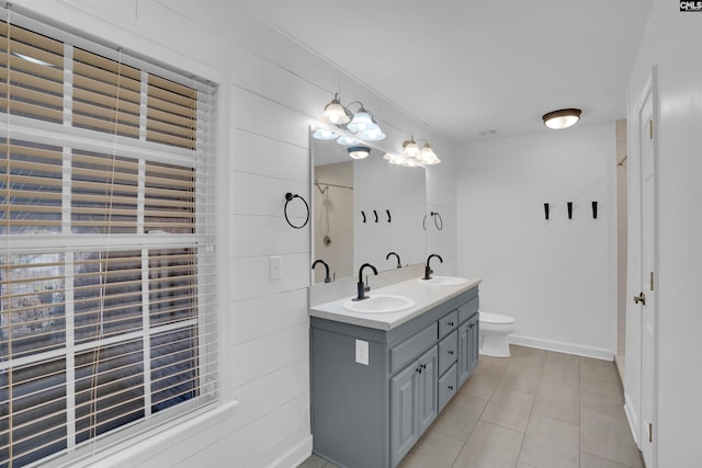 bathroom with double vanity, tile patterned flooring, toilet, and a sink