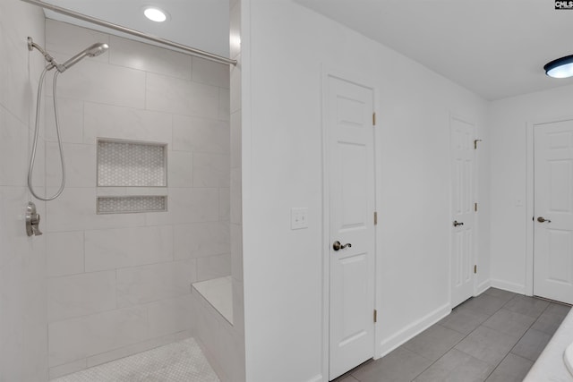 bathroom with tile patterned flooring, baseboards, and tiled shower