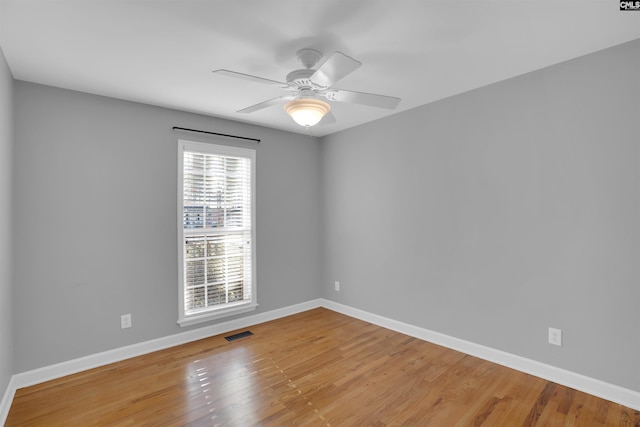 unfurnished room with baseboards, visible vents, ceiling fan, and wood finished floors