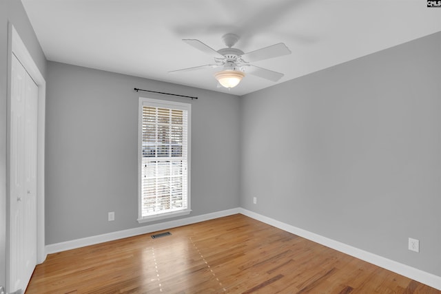 unfurnished room with light wood-style floors, baseboards, visible vents, and ceiling fan