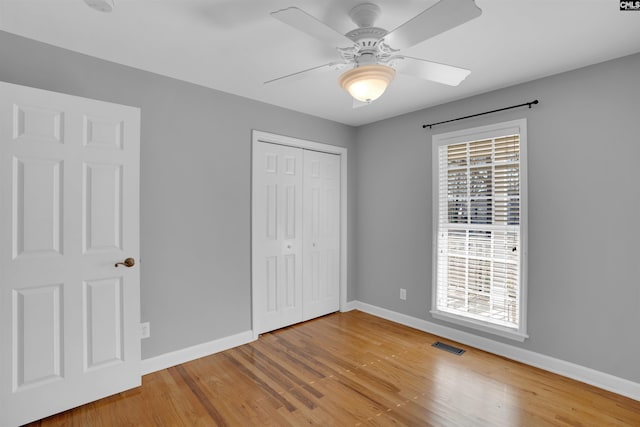 unfurnished bedroom with wood finished floors, visible vents, and baseboards