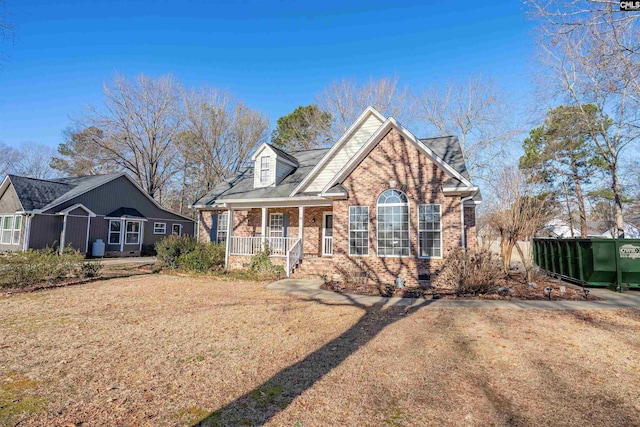 view of front facade with covered porch, brick siding, crawl space, and a front lawn