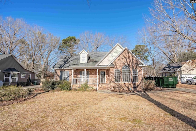 view of front of house featuring covered porch, brick siding, and a front lawn