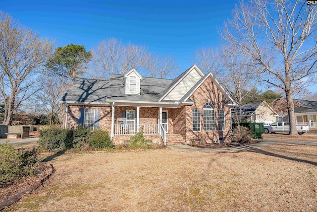 view of front of property with covered porch, brick siding, and a front lawn