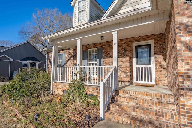 entrance to property with brick siding and a porch