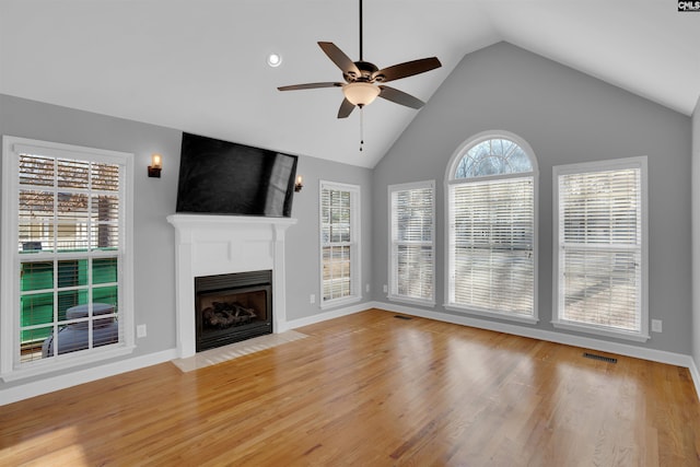 unfurnished living room with a fireplace with flush hearth, visible vents, light wood-style floors, and a ceiling fan