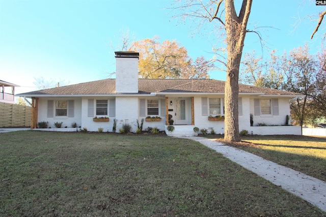 ranch-style house featuring a front lawn, a chimney, and brick siding