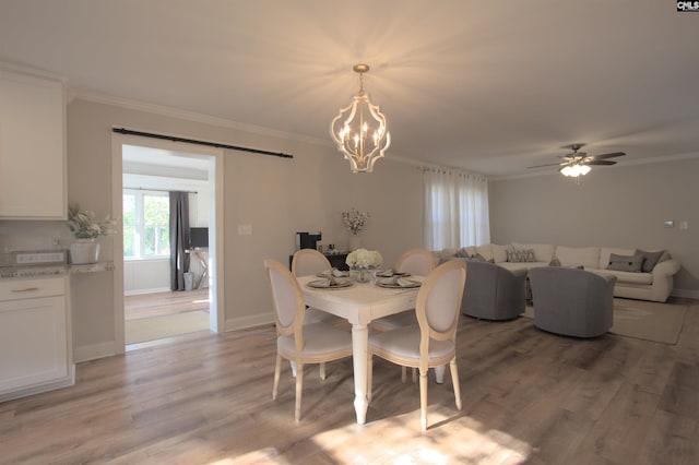 dining space with light wood-type flooring, a barn door, and ornamental molding