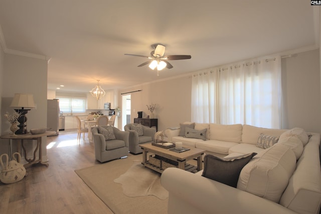 living room with ceiling fan with notable chandelier, crown molding, and wood finished floors