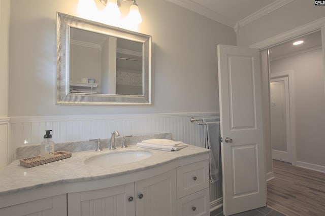 bathroom featuring ornamental molding, wainscoting, vanity, and wood finished floors