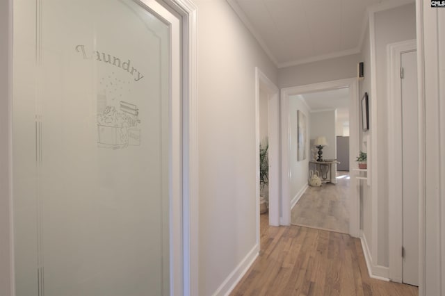 hall with ornamental molding, light wood-type flooring, and baseboards