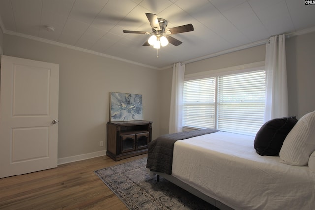 bedroom with ornamental molding, a ceiling fan, baseboards, and wood finished floors