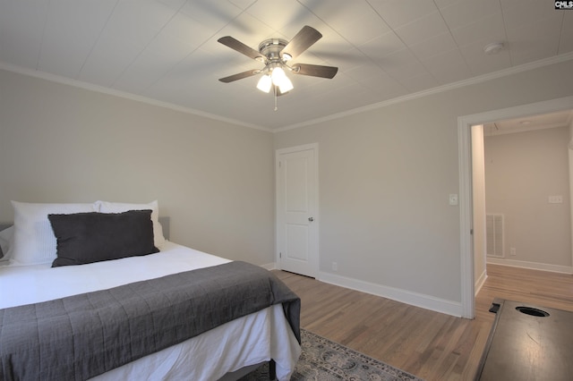 bedroom with visible vents, ornamental molding, ceiling fan, wood finished floors, and baseboards