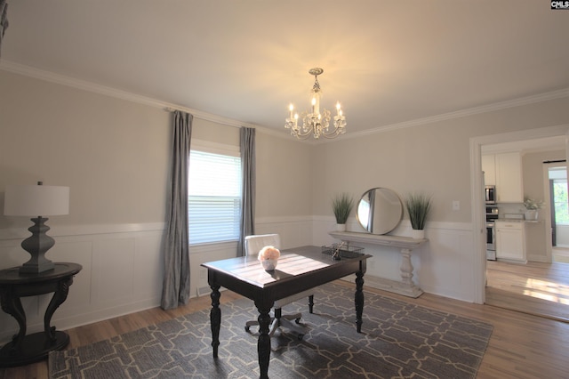 office area featuring a chandelier, light wood-type flooring, a wainscoted wall, and ornamental molding