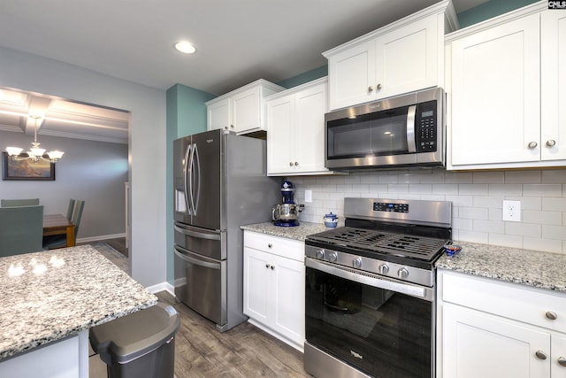 kitchen with decorative backsplash, dark wood-style floors, light stone counters, stainless steel appliances, and white cabinetry