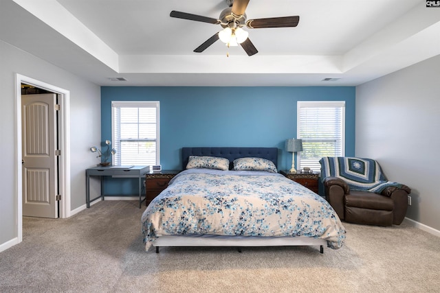 carpeted bedroom featuring a tray ceiling, multiple windows, and visible vents