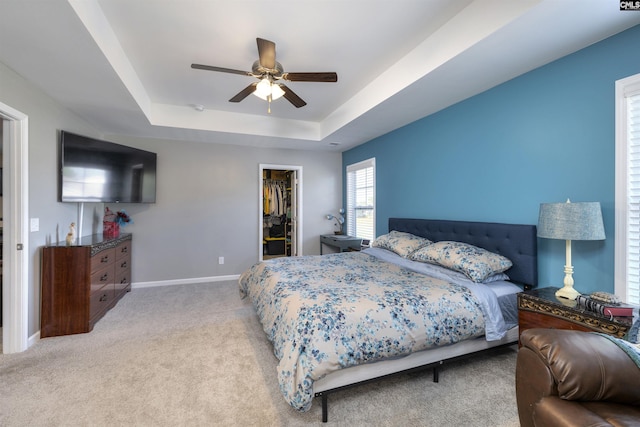 carpeted bedroom featuring ceiling fan, baseboards, a spacious closet, a closet, and a raised ceiling