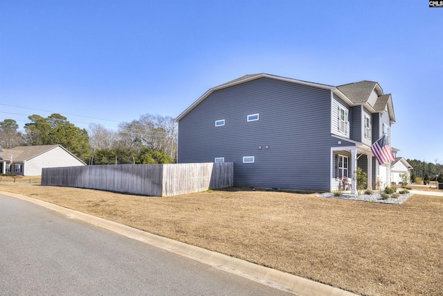 view of home's exterior with fence and a yard