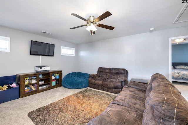 carpeted living area featuring ceiling fan, visible vents, and attic access