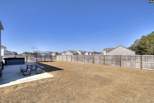 view of yard with a trampoline, a fenced backyard, and a patio